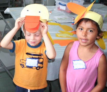 Two small children wearing paper duck masks they have made.